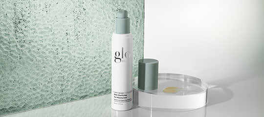 glo pump bottle and cap on round tray with textured green glass backdrop